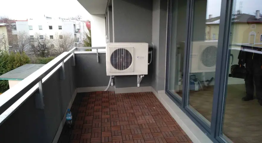 Klimatyzacja w bloku zamontowana na balkonie. Jednostka zewnętrzna chłodzi mieszkanie, zapewniając komfort.