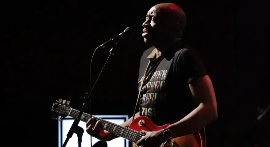 Musiker mit Gitarre und Mikrofon, trägt T-Shirt mit dem Titel von Otis Redding.