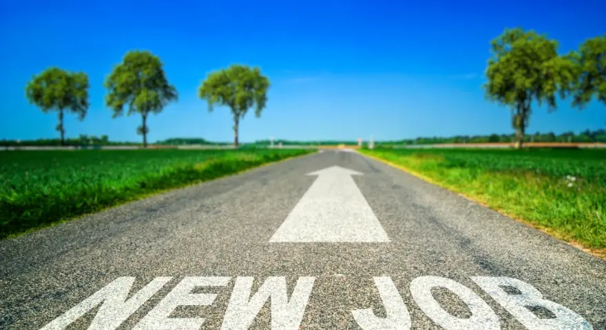 Strada asfaltata con freccia bianca e scritta "NEW JOB". Un percorso verso un futuro luminoso, ideale per chi sta pensando di cambiare lavoro a 30 anni.