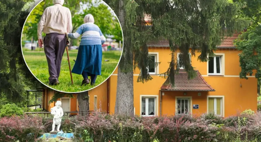 Spacer po parku przy sanatorium w Przerzeczynie Zdroju. Starsza para, wspierając się laską, cieszy się spokojnym popołudniem.