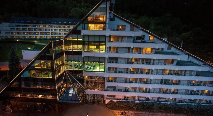 Nowoczesny hotel Klimczok Resort & Spa nocą, z oświetlonymi oknami i wejściem. Wiele pozytywnych hotel klimczok resort & spa opinie potwierdza jego urok.