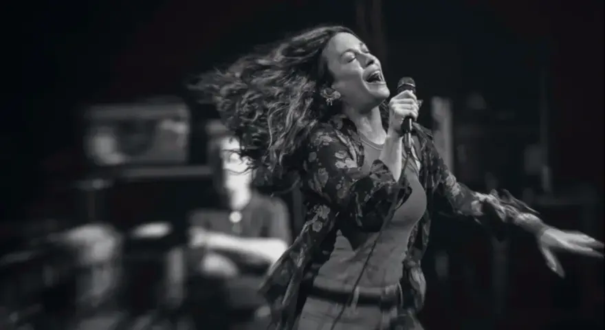 Energetyczny alanis morissette koncert, wokalistka śpiewa z pasją, włosy rozwiane w locie.