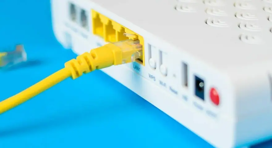 Żółty kabel sieciowy podłączony do portu LAN routera i modemu.