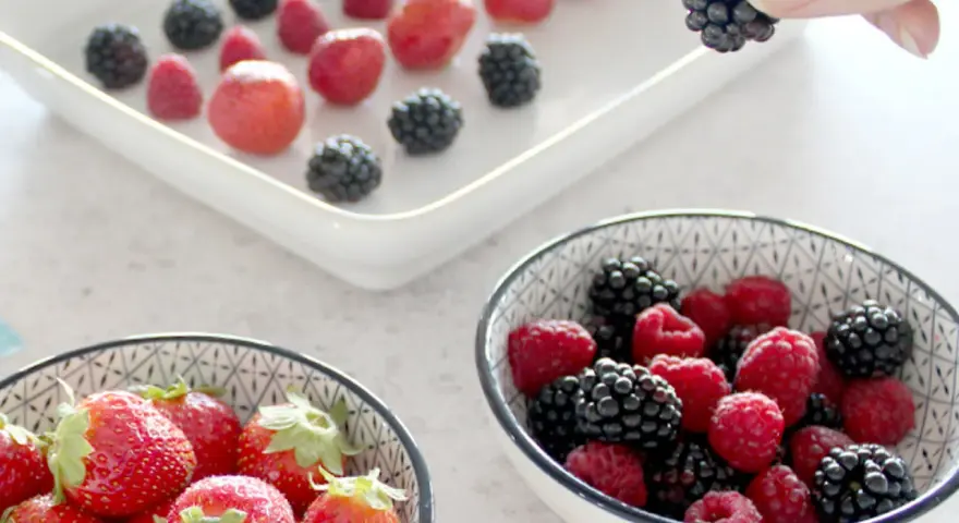 Frische Beeren, darunter Erdbeeren, Himbeeren und Brombeeren, werden für die Lagerung vorbereitet. Man kann Erdbeeren einfrieren, um sie später zu genießen.