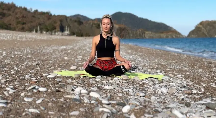 Frau in Meditation am Strand, tiefe Konzentration auf die Wellen.