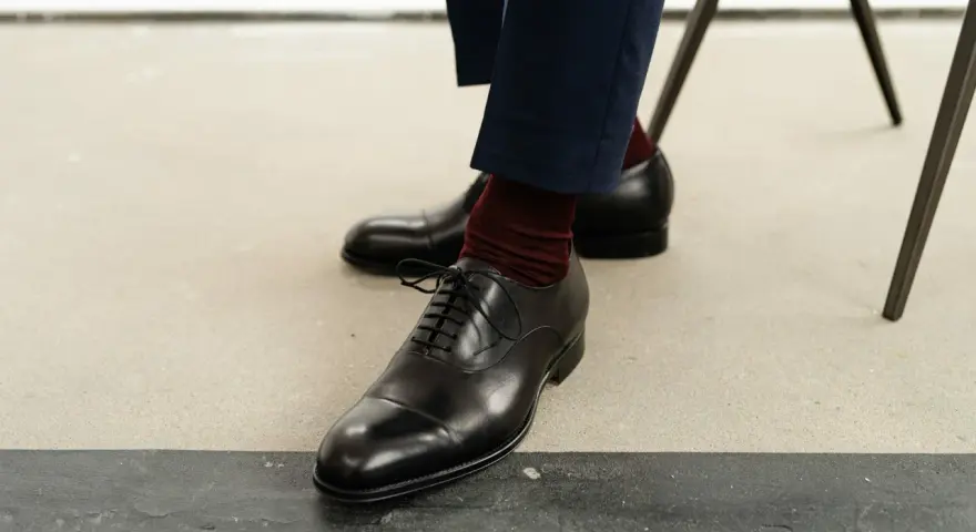 Eleganckie, czarne oksfordy z ciemnoczerwonymi skarpetkami. Klasyczne rodzaje butów męskich, idealne do garnituru.