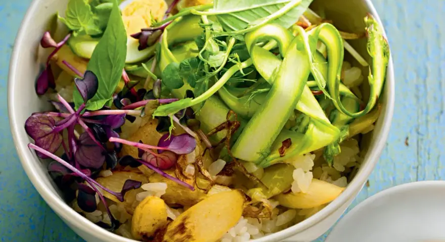 Eine bunte Spargel Bowl mit Reis, Ei, Sprossen und frischen Kräutern, appetitlich angerichtet.