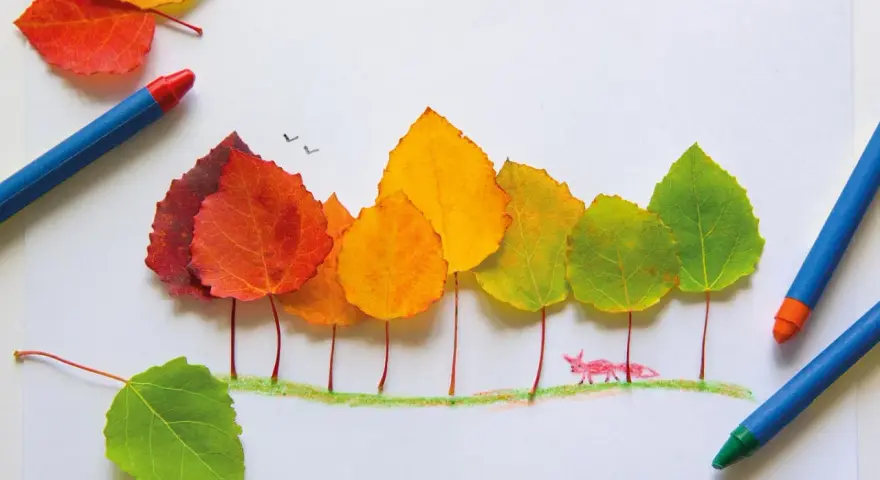 Bunte Herbstblätter werden zu Bäumen arrangiert. Ein kleiner Fuchs schaut neugierig hervor. Perfekt für Herbst basteln Kinder!
