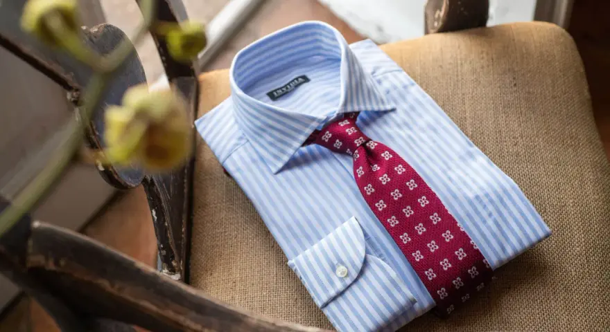 Camicia bianca a righe azzurre con cravatta bordeaux a fantasia floreale, pronta per un abito blu.