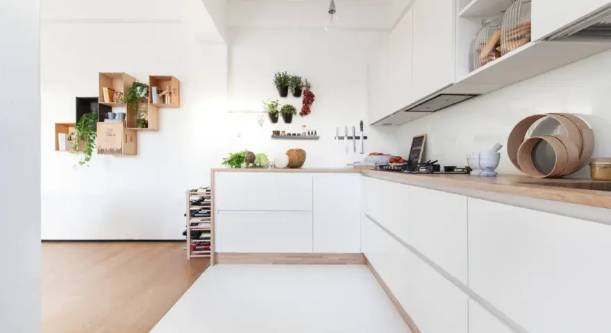 Progetto cucina angolare piccola: mobili bianchi minimalisti, piano in legno, mensole a muro con piante e vasi.