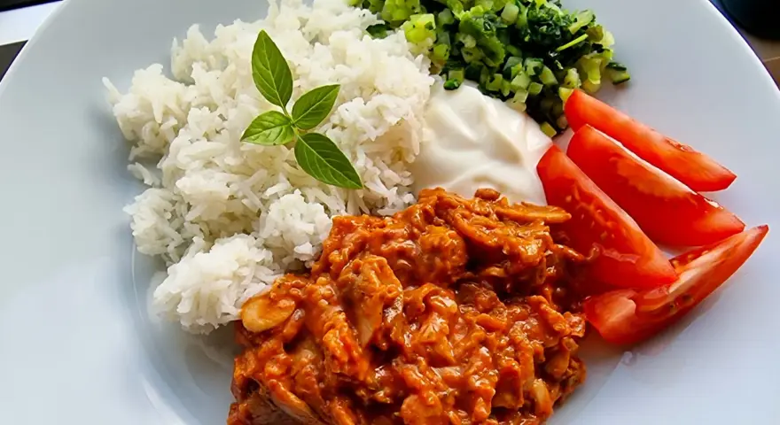 En smakrik kebabgryta med ris, serverad med fräscha tomater och en klick vit sås. En perfekt middag!