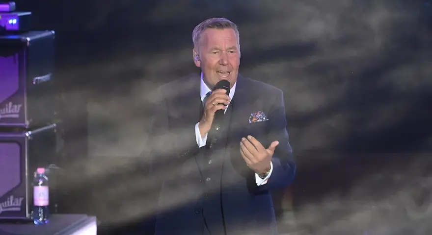Roland Kaiser singt in Berlin. Der Künstler trägt einen dunklen Anzug und hält ein Mikrofon.