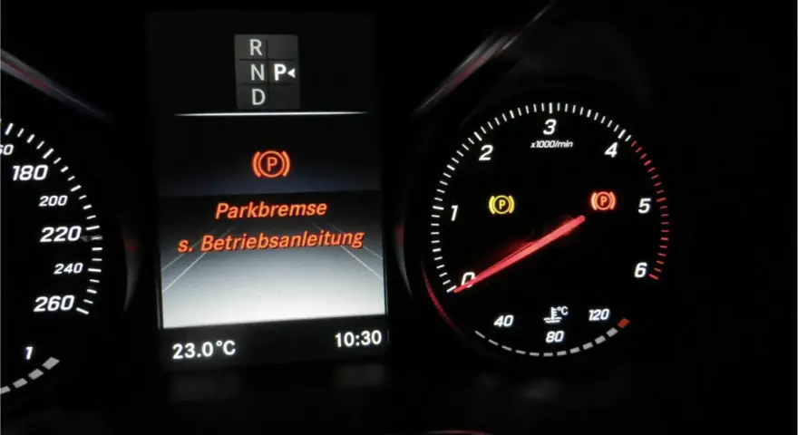 Mercedes-Armaturenbrett: gelbe Warnleuchte für die Feststellbremse leuchtet. Die Anzeige "Parkbremse" und "s. Betriebsanleitung" ist sichtbar.