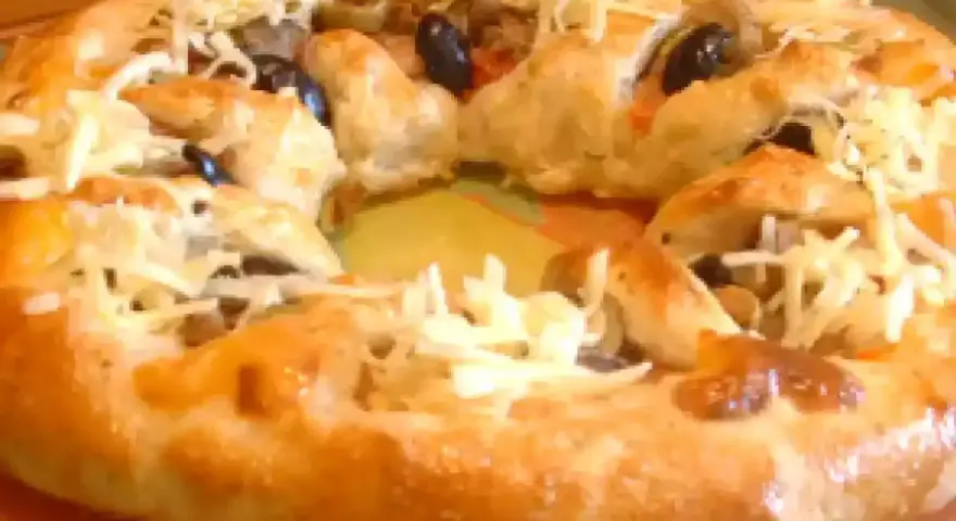 Pizza maison avec une croûte dorée, garnie d'olives noires et de fromage râpé. Parfait pour une recette pâte à pizza rapide.