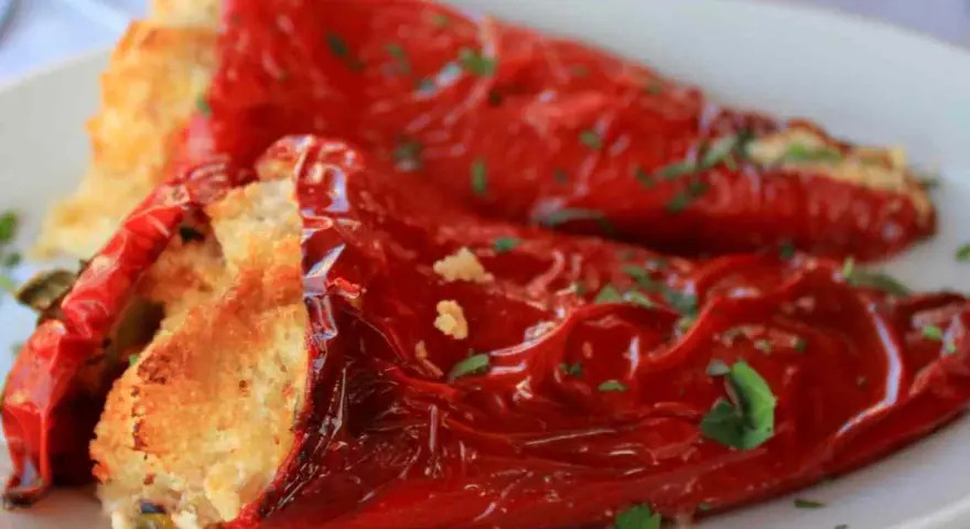 Peperoni ripieni in padella, dorati e profumati, con un ripieno invitante e una spolverata di prezzemolo fresco.