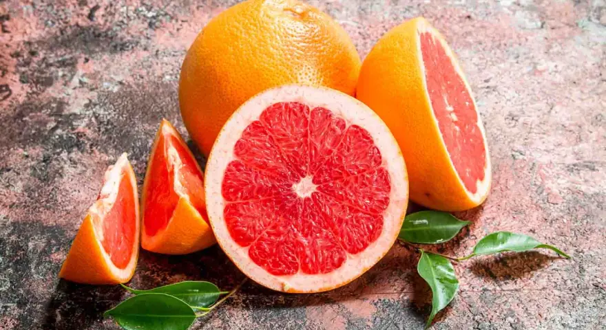 Saftige Grapefruits, frisch aufgeschnitten und als Spalten, mit grünen Blättern. Grapefruit gesund und lecker.