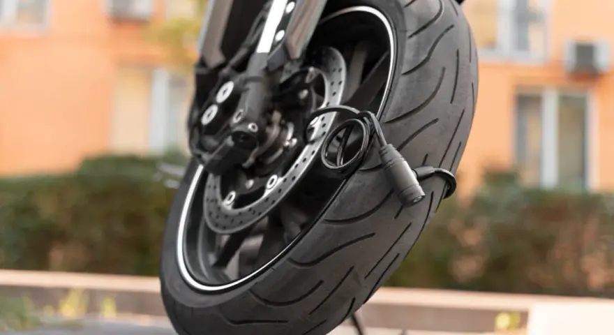 Zabezpieczenie motocykla przed kradzieżą: gruby, czarny łańcuch oplatający oponę i tarczę hamulcową.