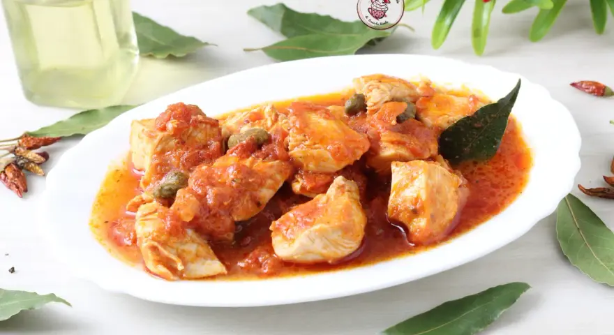 Un invitante pollo alla pizzaiola, con pezzi succulenti immersi in una ricca salsa di pomodoro, capperi e profumate foglie di alloro.