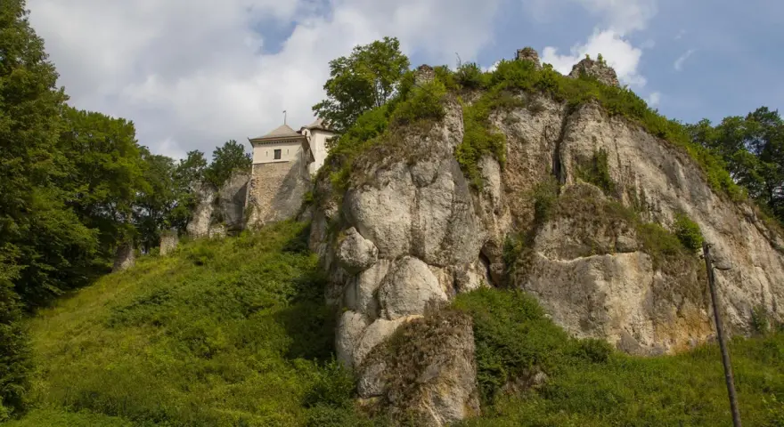 Zamek w Ojcowie góruje nad wapiennymi skałami, otoczony bujną zielenią.