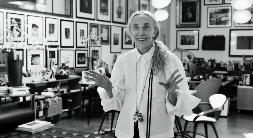 Donna elegante con camicia bianca, un'icona di stile che incarna la moda di Milano. Le sue mani aperte raccontano storie di creatività e design.