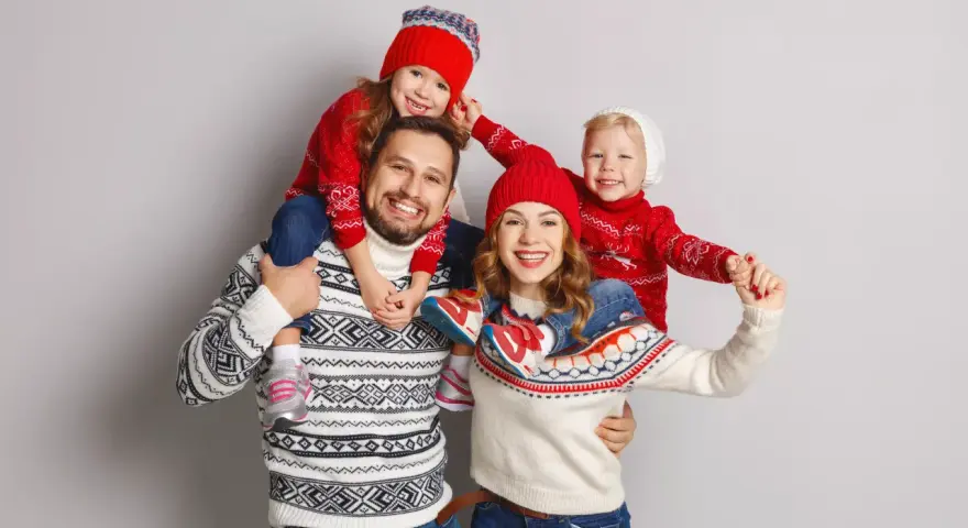 Famiglia felice con maglioni natalizi coordinati, un'ottima ispirazione per idee outfit natale.