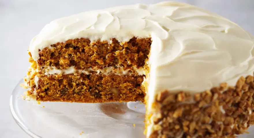 Tarta de zanahoria y queso con glaseado cremoso y nueces picadas en los bordes. ¡Un postre irresistible!