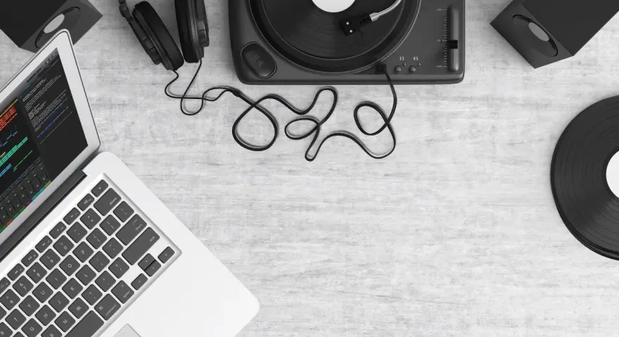 Laptop z programem do produkcji muzyki, gramofon, słuchawki i głośniki. Tworzenie utworu muzycznego z samplera.