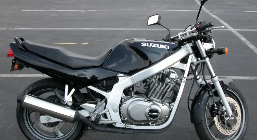 Czarny motocykl Suzuki GS 500 z chromowanym wydechem stoi na pustym parkingu.