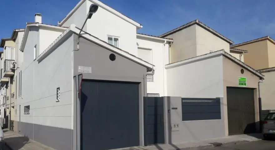 Fachada de casa con garaje, lista para como pintar una pared exterior en mal estado.