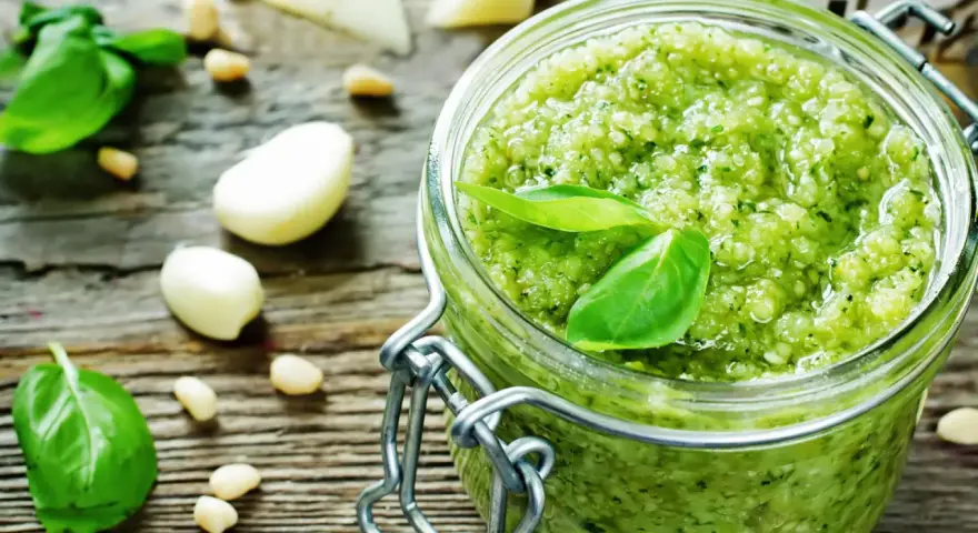 Frisches Pesto machen: Basilikum, Pinienkerne, Knoblauch und Parmesan auf rustikalem Holz.