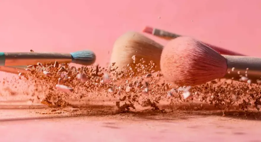 Pudry do makijażu w chmurze pyłu, pędzle do aplikacji pudru setting.