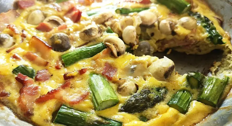 Pyszny stek ze szparagami, boczkiem i pieczarkami zapieczony w jajku. Idealny na śniadanie lub lekki obiad.