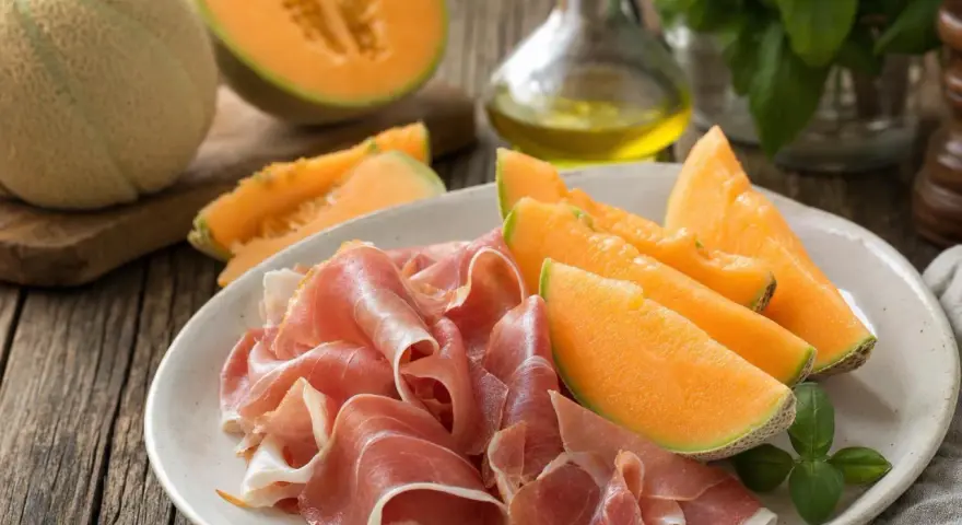 Piatto con fette di prosciutto e spicchi di melone, un classico antipasto italiano.