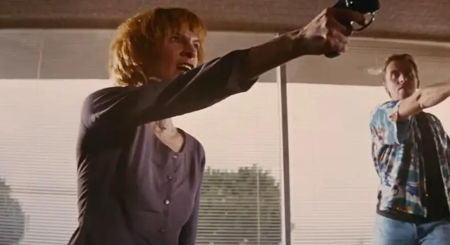 Donna e uomo puntano pistole, in una scena che ricorda un cliffhanger traduzione.