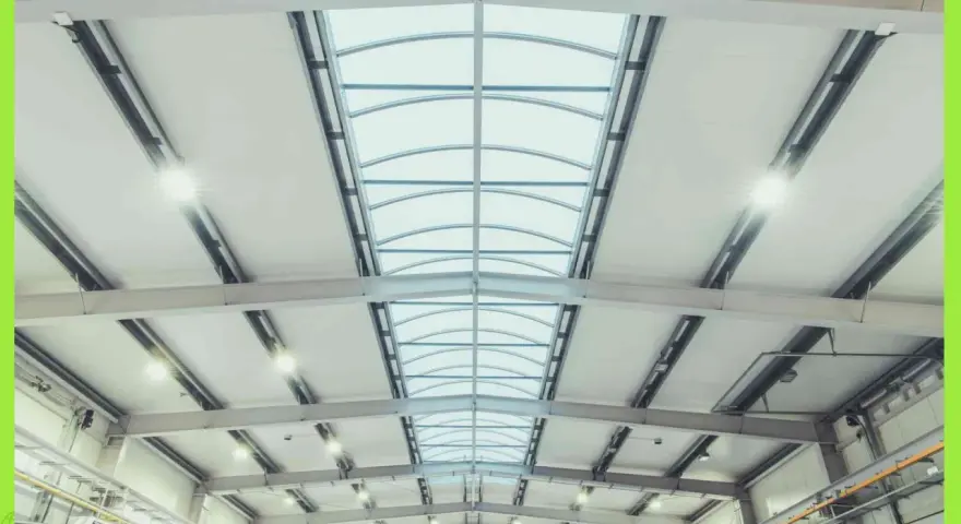 Interno di un capannone con luminose coperture industriali e lucernari curvi che illuminano lo spazio.