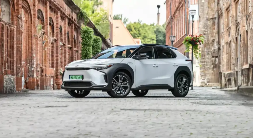 Biała Toyota bZ4X na brukowanej uliczce, gotowa na długie podróże. Sprawdź jej imponujący zasięg!