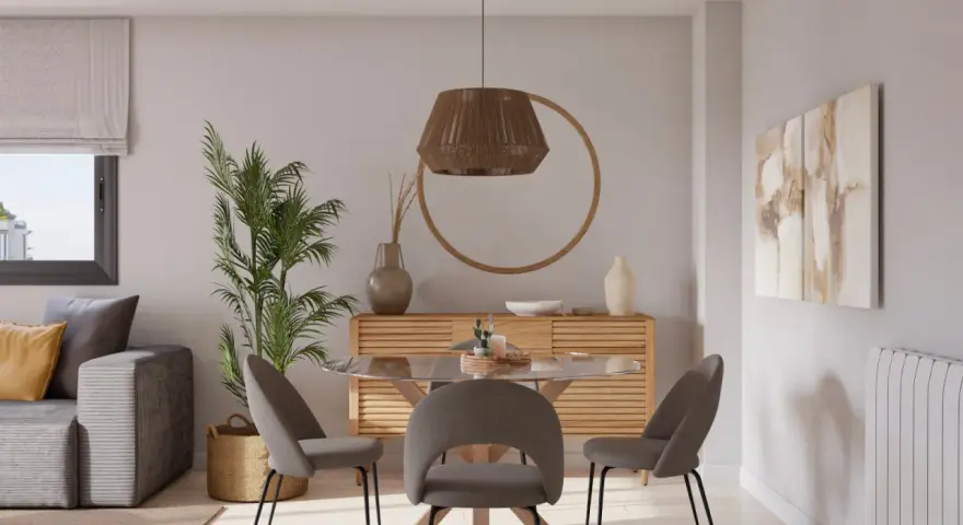 Acogedor salon comedor muy pequeño con sofá gris, mesa redonda de cristal y sillas tapizadas. Decoración natural con planta y cesta.