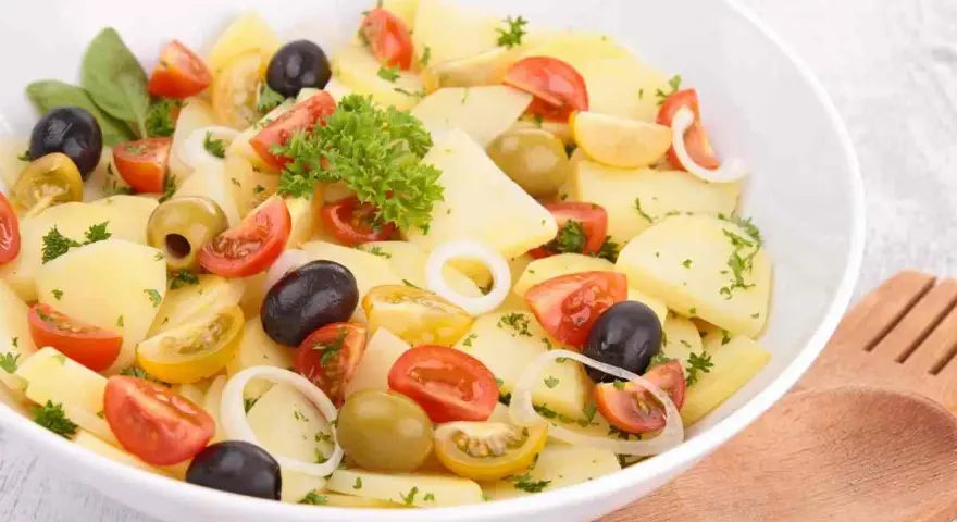 Insalata di patate pugliese con pomodorini, olive nere e verdi, cipolla e prezzemolo fresco. Un piatto estivo e saporito.