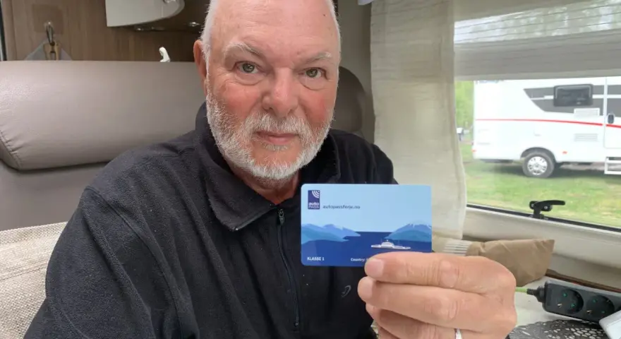 Man håller upp ett kort med texten "autopassferje.no", redo för resor mellan Norge och Sverige.