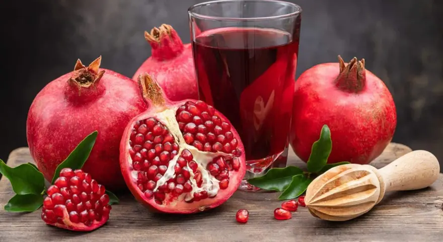 Frische Granatäpfel und Saft auf einem Holztisch. Ein gesunder Genuss, besonders in der Schwangerschaft.
