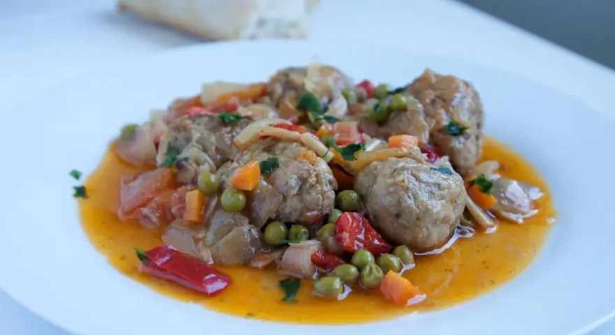 Albondigas a la jardinera, jugosas y sabrosas, con guisantes, zanahoria y pimiento rojo en una salsa dorada.