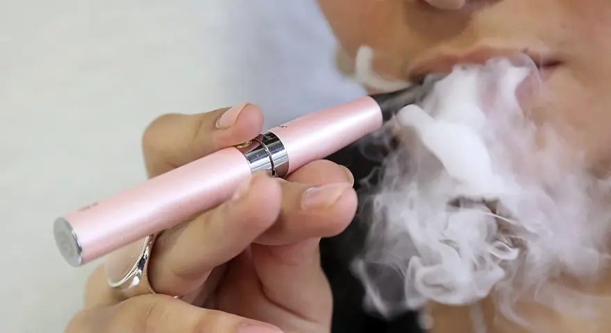 Persona usa un vapeador para dejar de fumar, exhalando una gran nube de vapor.