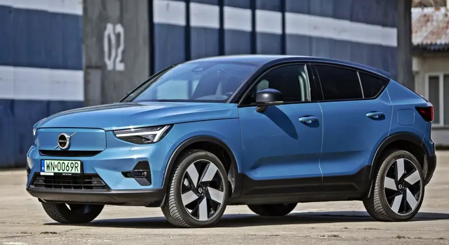 Niebieskie Volvo C40, elektryczny SUV coupe, parkuje przed budynkiem z numerem "02".