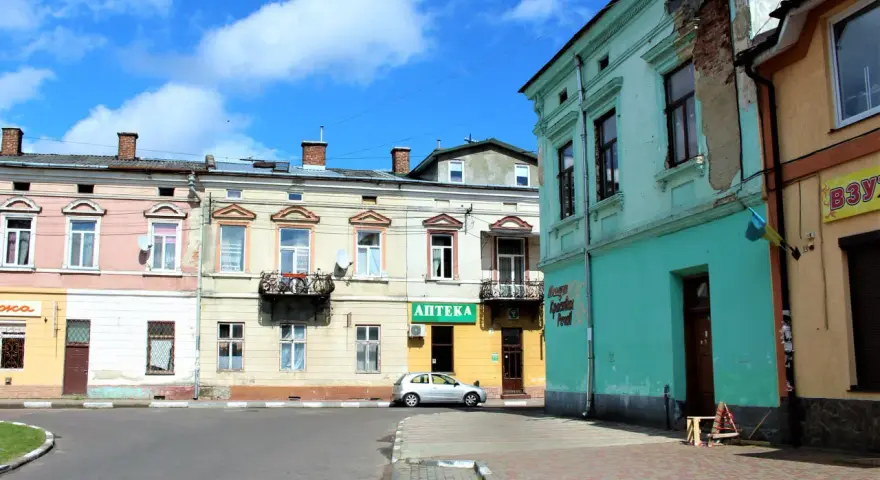 Kolorowe kamienice przy ulicy, gdzie mój stryj kiedyś mieszkał. Srebrny samochód zaparkowany obok apteki.
