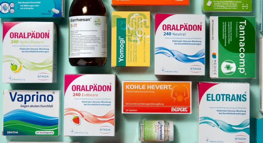 Medikamentenpackungen und eine Flasche Saft gegen Durchfall, auf blauem Hintergrund.