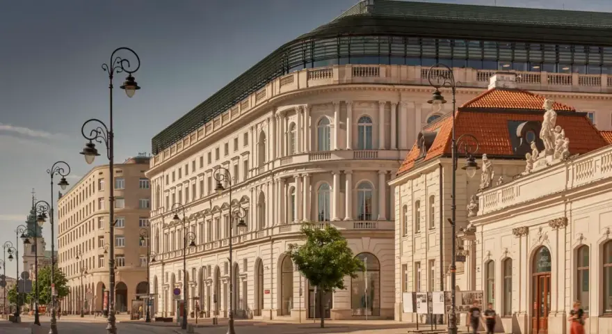 Elegancka kamienica z nowoczesnym dachem, być może najdroższy hotel w Polsce, przy słonecznej ulicy z zabytkowymi latarniami.