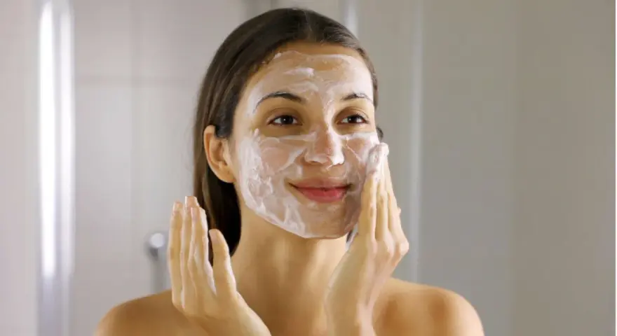 Frau mit Schaum im Gesicht, die ihre Haut reinigt. Ein Schritt im Double Cleansing für reine Haut.