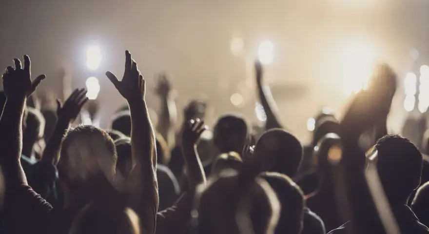 A crowd with raised hands, bathed in warm light, as if in a moment of shared worship or during powerful christian chants.