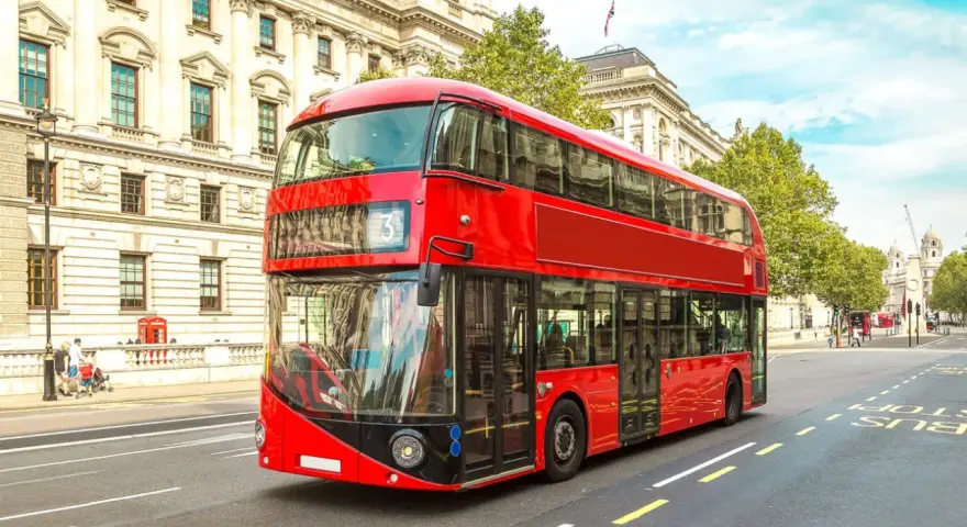 Ikoniczny czerwony autobus piętrowy na ulicy w Londynie, symbol komunikacji miejskiej.