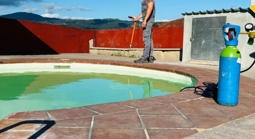Técnico trabajando en el borde de una piscina, con equipo para impermeabilizar piscina.